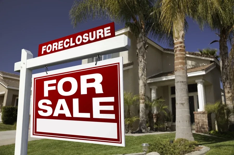 Large foreclosure sign in front of a Florida home with palm trees