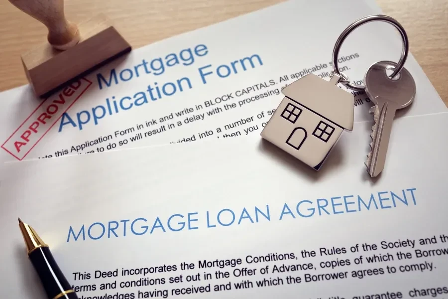 Approved mortgage application with house keys and a pen resting on a loan agreement